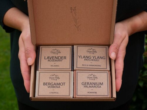 Open gift box with four handmade soaps from Three Hills Soap in labeled rows