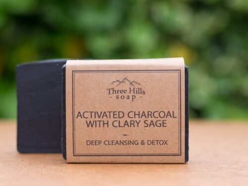 Activated Charcoal soap bar with rustic label on light surface and green outdoor background