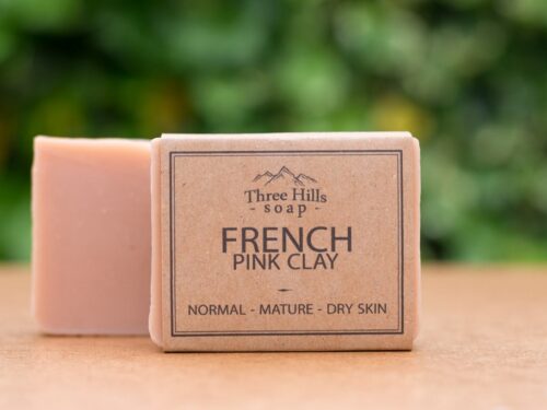 French Pink Clay soap bar with rustic label on light surface and green outdoor background