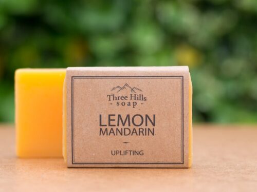 Lemon Mandarin soap bar with rustic label on light surface and green outdoor background