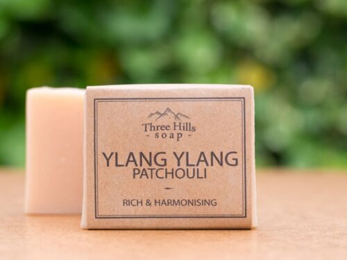 Ylang Ylang Patchouli soap bar with rustic label on light surface and green outdoor background