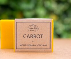 Carrot soap bar with eco-friendly packaging and green blurred background