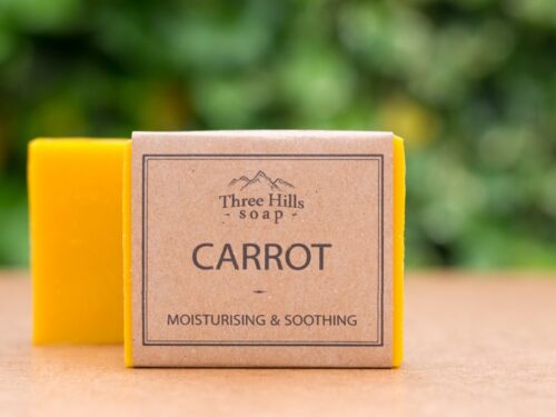 Carrot soap bar with eco-friendly packaging and green blurred background