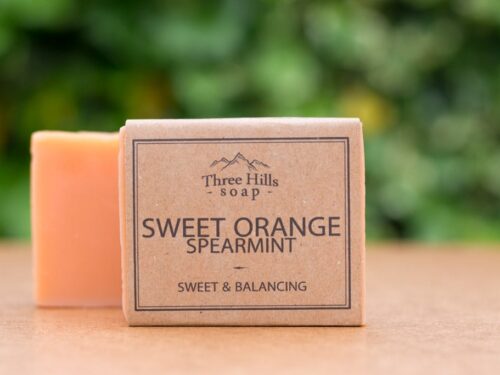 Sweet Orange Spearmint Castile Olive soap bar with rustic label on light surface and green background