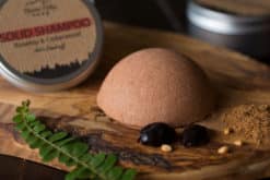 Anti-dandruff solid shampoo bar placed on the wooden surface with a black background