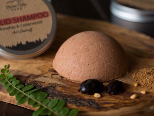 Anti-dandruff solid shampoo bar placed on the wooden surface with a black background