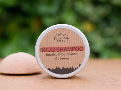 anti-dandruff solid shampoo with rustic label on light surface and green outdoor background