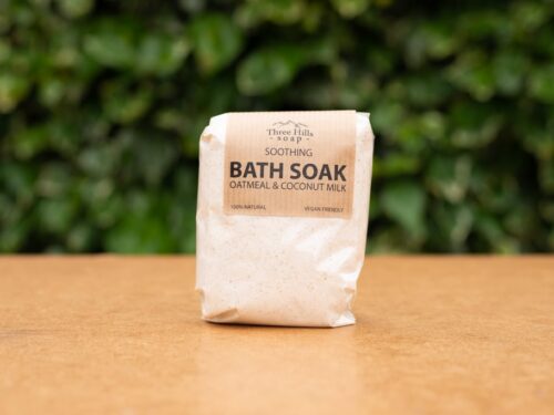 Soothing Bath Soak with oatmeal and coconut milk on wood surface with green background