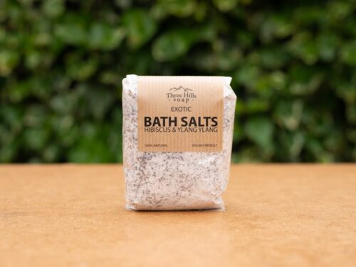 Exotic Bath Salts with hibiscus and ylang ylang on wood surface with green background