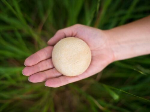 Hand holding Solid Shampoo bar for Hair Growth with a green background