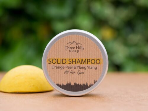 solid shampoo for all hair types with rustic label on light surface and green outdoor background
