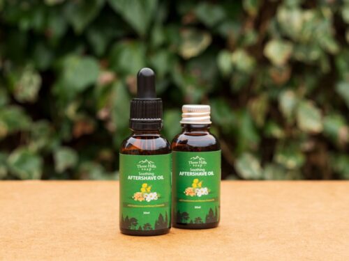 Two bottles of Soothing Aftershave Oil with green labels on outdoor background