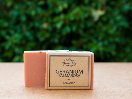 Geranium Palmarosa soap bar with rustic label on light surface and green background