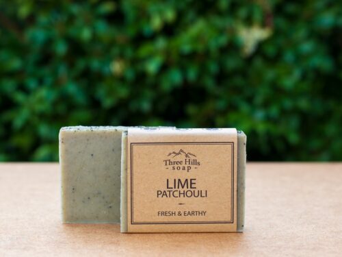 Lime Patchouli soap bar with rustic label on light surface and green outdoor background