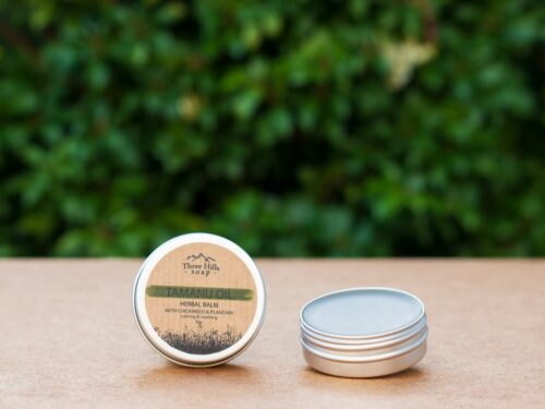Tamanu oil herbal salve in round tin with botanical label