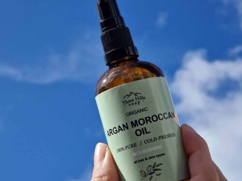 Bottle of Organic Argan Moroccan Oil by Three Hills Soap held up to the sky