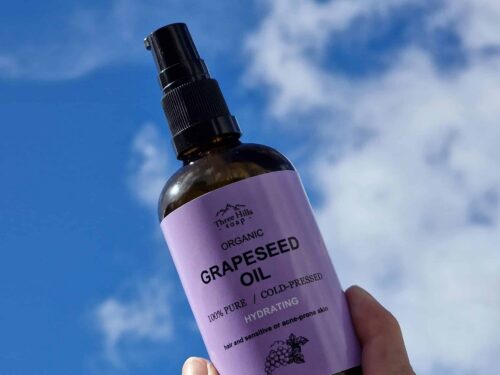 Three Hills Soap Organic Grapeseed Oil bottle held in hand with sky background
