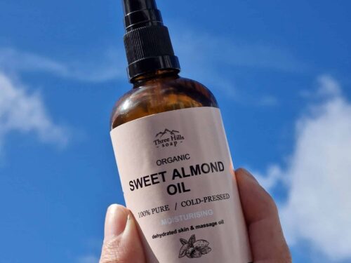 Three Hills Soap Organic Sweet Almond Oil held in hand under blue sky