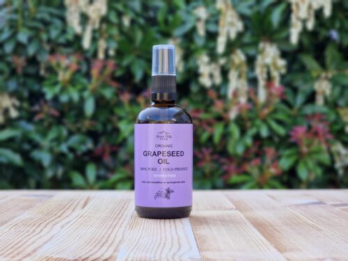 Three Hills Soap Organic Grapeseed Oil in 100ml amber bottle with pump, placed on wood with green outdoor background
