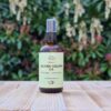 Three Hills Soap Organic Jojoba Golden Oil in 100ml amber glass bottle with pump, displayed outdoors on wood with blurred greenery