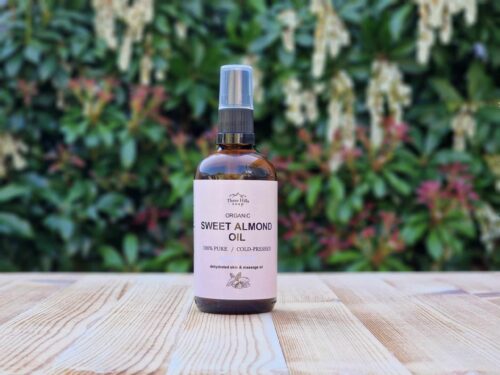 Three Hills Soap Organic Sweet Almond Oil in 100ml amber bottle with pump, sitting on wood with green background