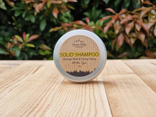 A travel shampoo bar for all hair types in the tin on the wooden surface.