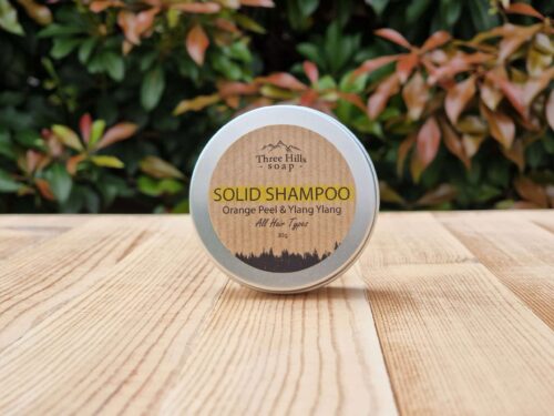 A travel shampoo bar for all hair types in the tin on the wooden surface.