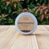 A travel shampoo bar for hair growth in the tin on the wooden surface.
