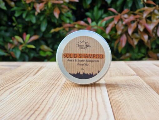 A travel shampoo bar for normal hair in the tin on the wooden surface.