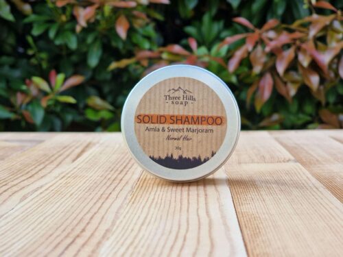 A travel shampoo bar for normal hair in the tin on the wooden surface.